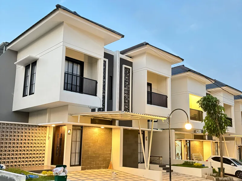 Deretan rumah dua lantai tipe Azura di Aura Park saat senja, fasad putih dengan balkon dan carport