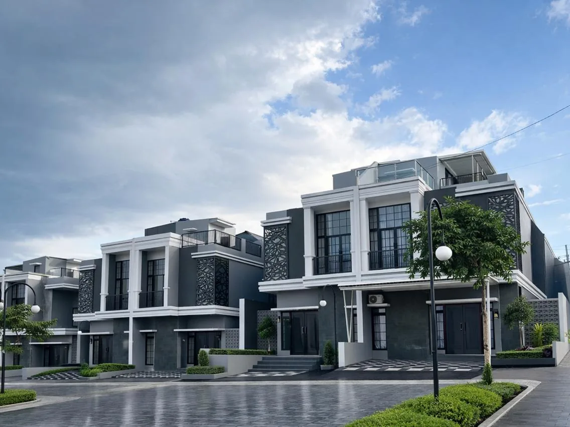 Rumah tipe Alexandria 109/104 di Aura Park: deretan rumah dua lantai berfasad abu-abu dan putih dengan rooftop, jalan paving dan lampu taman